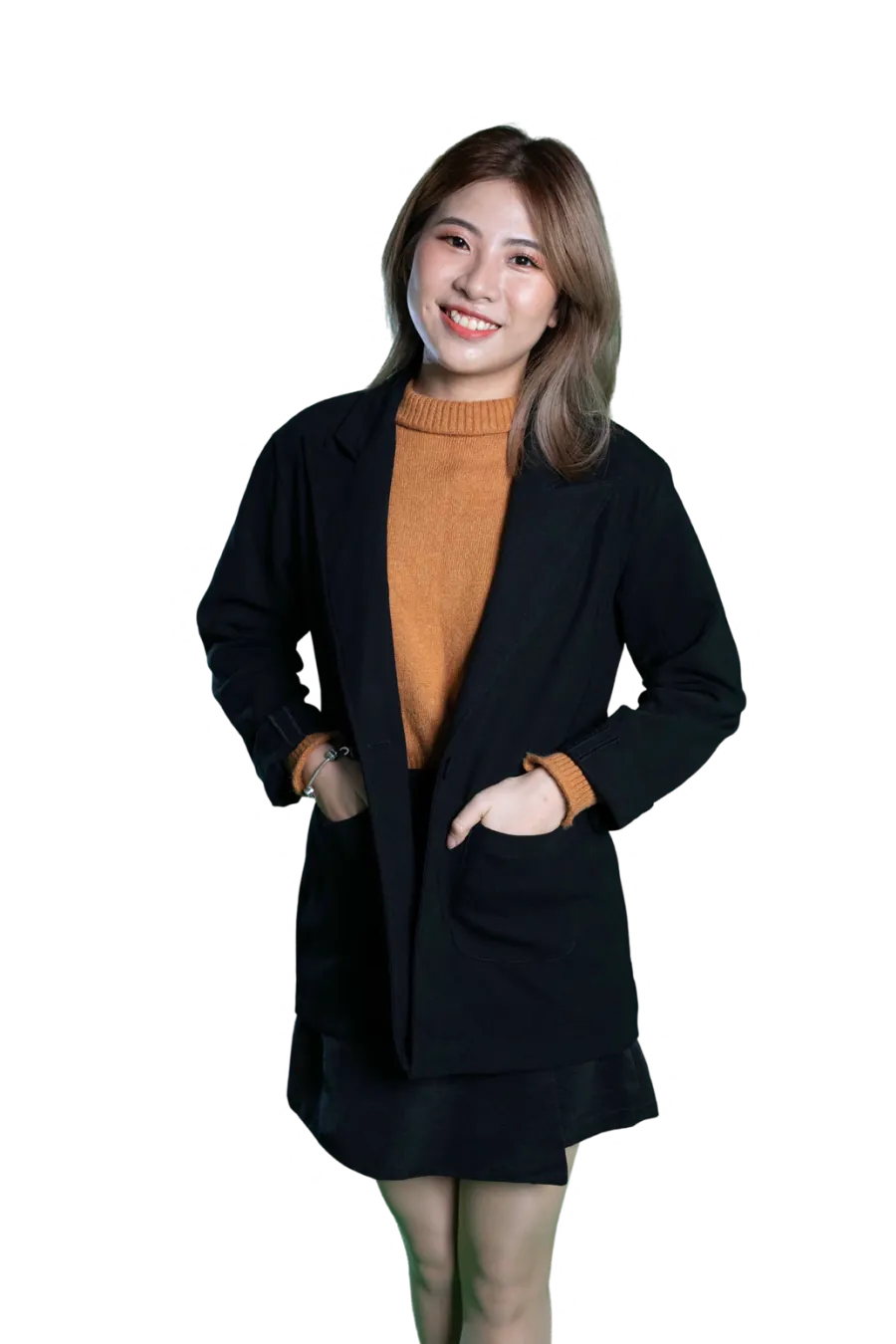 Nhi Duong, standing with her hands in the pockets of a black coat over an amber jumper
